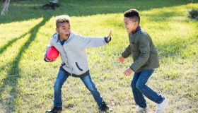 Two boys playing football in back yard