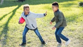 Two boys playing football in back yard