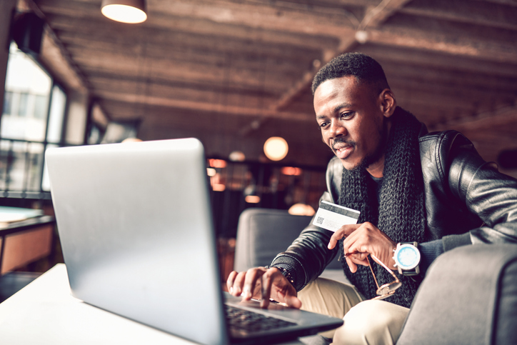 Happy African Male Online Shopping In Coffee Bar