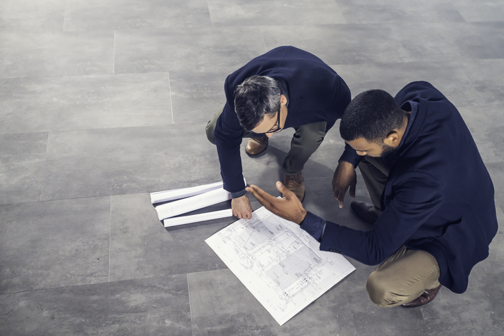 Architects talking about blueprints while crouching on the floor