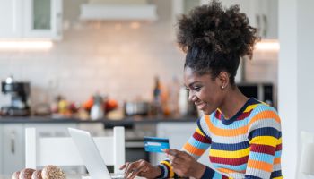 Smiling afro woman shopping online at home