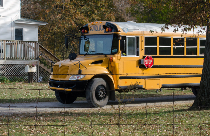 A Large Yellow School Bus Stops To Drop Off Students At Their Home