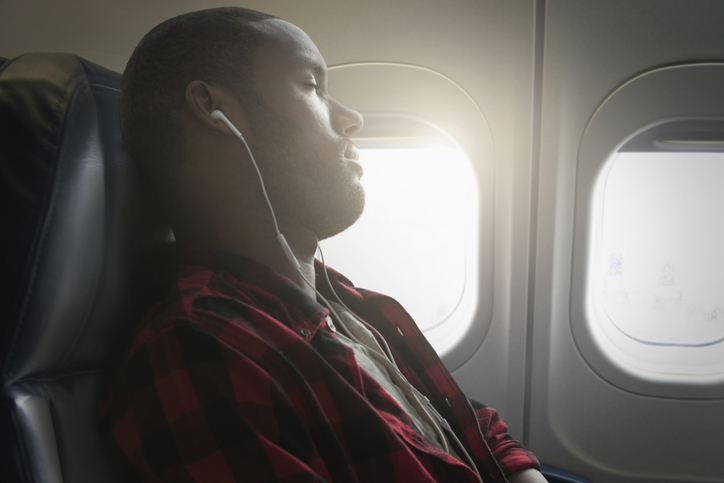 Black man listening to earbuds on airplane