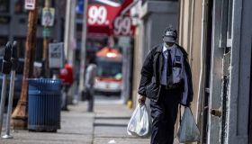 A Man Wearing A Security Guard Uniform and a Mask Walks in Hempstead, New York Carrying Groceries