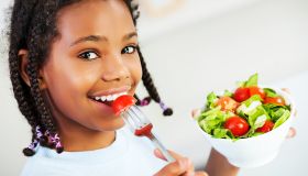 Little girl eating vegetable salad.