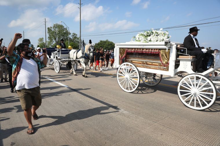 People follow and watch as a horse-drawn hearse containing the remains of George Floyd makes its way to the Houston Memorial Gardens cemetery
