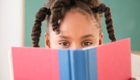 African American girl reading book in classroom