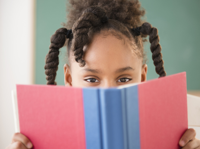African American girl reading book in classroom