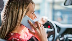 Young woman talking on phone while driving a car.
