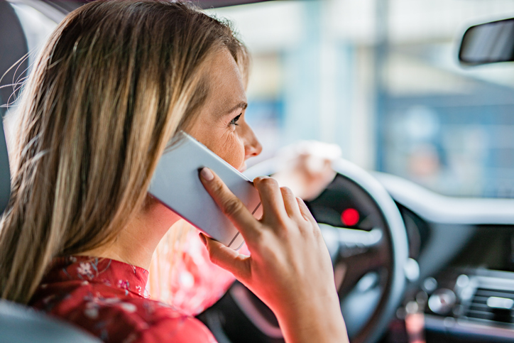 Young woman talking on phone while driving a car.