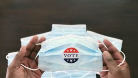 Woman Holds Face Mask With "Vote" Sticker