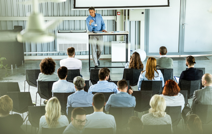 Above view of male leader giving a speech to large group of entrepreneurs.