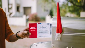 Man putting voting ballot to mailbox.
