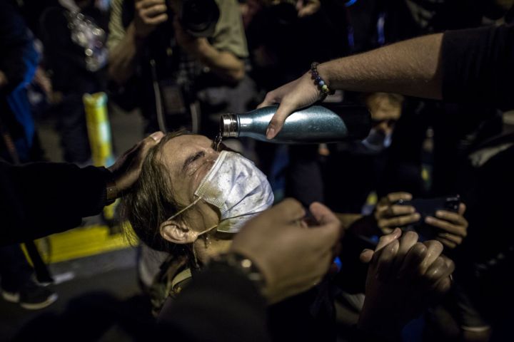 An anti-Trump demonstrator has her eyes rinsed after police...