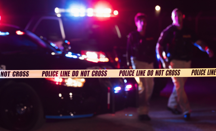 Two policemen behind crime scene tape