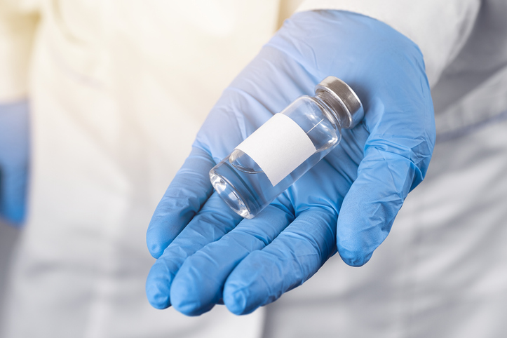 A doctor in a white coat and protective gloves holds the medicine in a glass ampoule. The vaccine for covid-19 or for colds and flu is in the hands of a nurse. The concept of treatment and prevention of the spread of infection, virus and pneumonia.