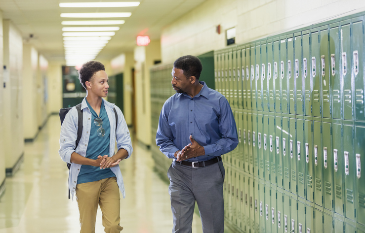 Teacher and high school student walking in hallway