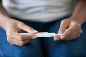 Mid section of young woman holding pregnancy test