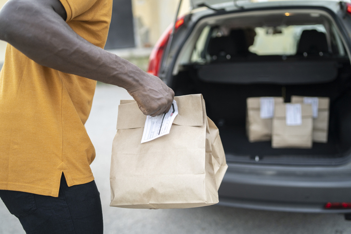 Close up of a curbside service staff holding paper bags