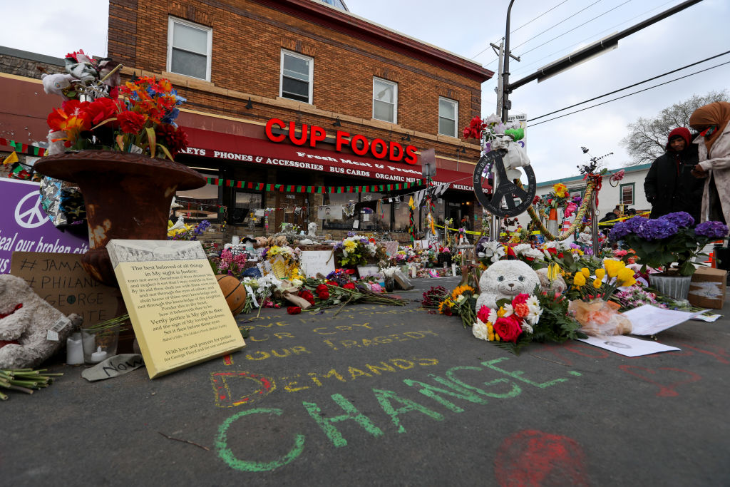 People lay flowers at a memorial in George Floyd Square...