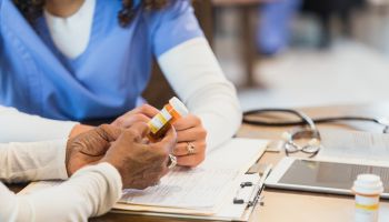 Unrecognizable senior woman asks nurse question about medication