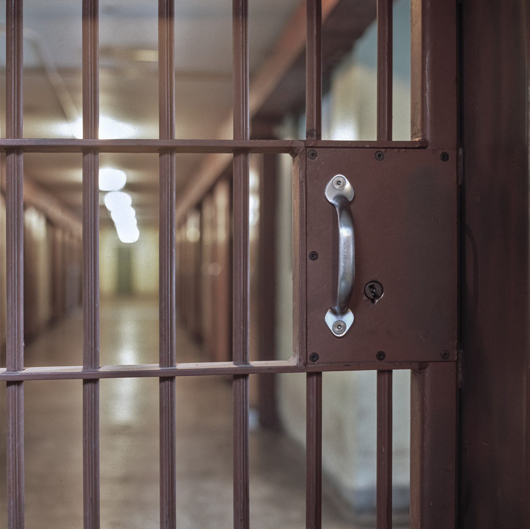 locked prison door with bars, hallway and prison cells