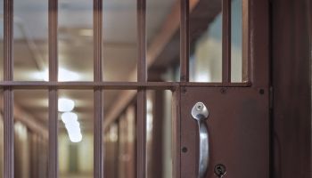 locked prison door with bars, hallway and prison cells