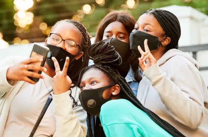 Teenage friends with face masks taking selfie outdoors
