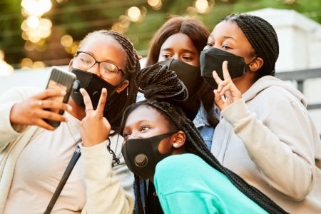 Teenage friends with face masks taking selfie outdoors