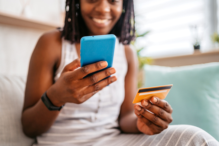 Woman shopping from couch with credit card and phone