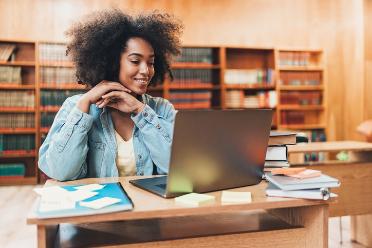 Student reading from a laptop in the library
