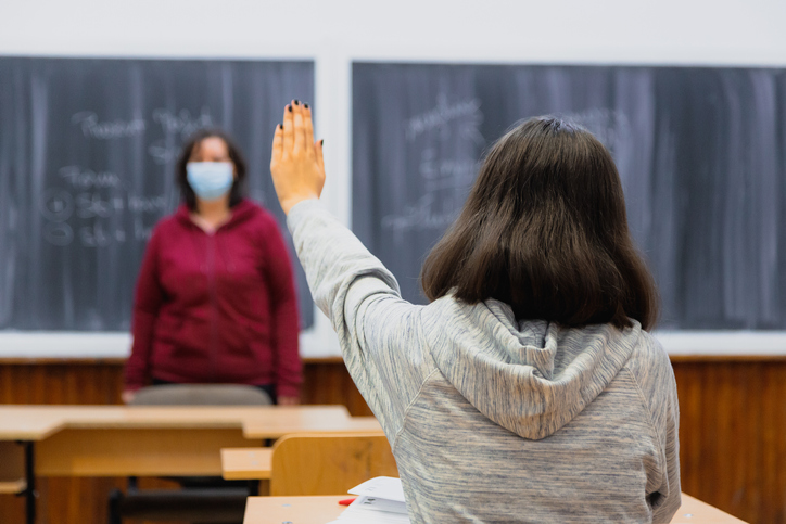 High school student with arm raised in classroom