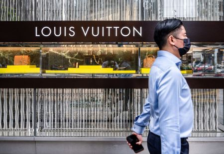 A man walks past the French luxury fashion brand Louis...