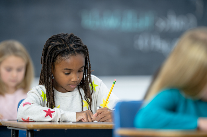 Multi-Ethnic Elementary Students Writing in Class