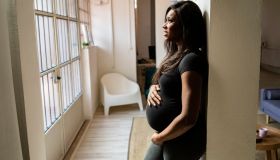 Thoughtful young pregnant woman leaning against column at home