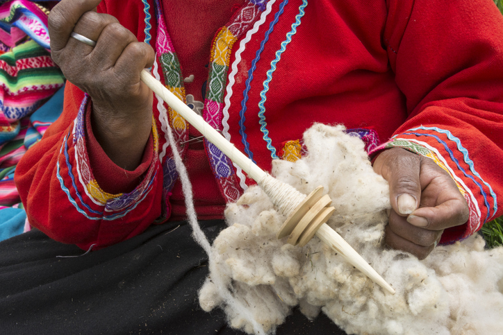 Quechua woman with alpaca wool and tool to spin it into yarn; El Parador de Moray, Sacred Valley, Peru.