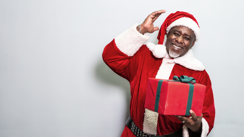 Santa Claus holding christmas gift on grey background