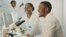 Diverse team working in modern laboratory. Woman and man joking during research