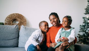 Portrait of Happy Mother Sitting with her Daughter and Son on a Sofa at Home