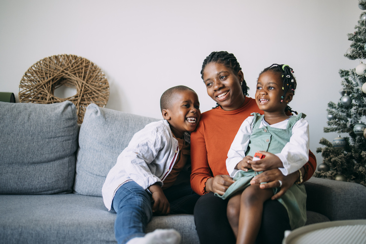 Portrait of Happy Mother Sitting with her Daughter and Son on a Sofa at Home
