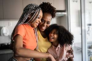 Mother and daughters embracing at home