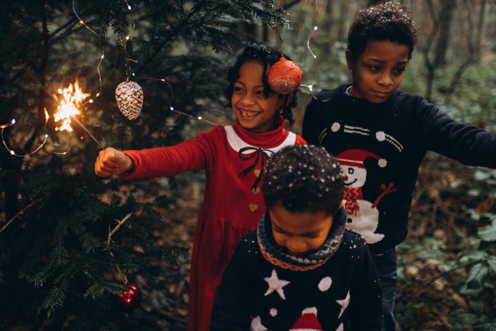 Children playing with sparklers in fairy forest on Christmas.