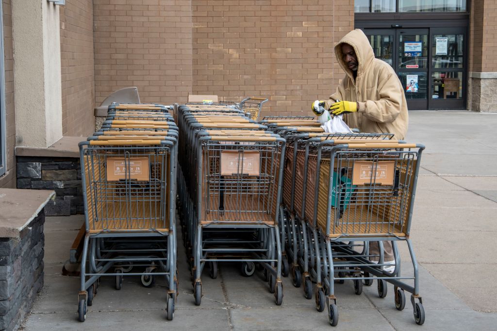 Liquor store employee cleans and disinfects the shopping carts to help stave off the coronavirus for customers, Roseville, Minnesota.