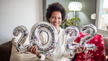 Woman holds balloons in shape of numbers 2022 and celebrating New Year