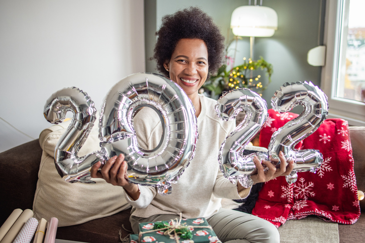 Woman holds balloons in shape of numbers 2022 and celebrating New Year