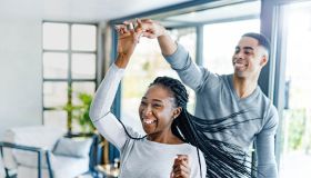 Cheerful African American couple dancing at home.
