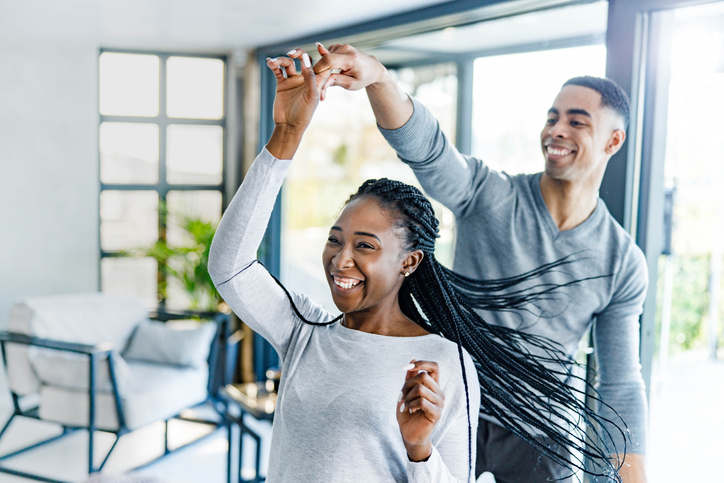Cheerful African American couple dancing at home.