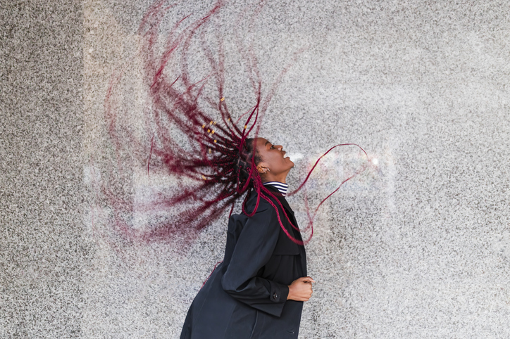 Young woman tossing hair by wall