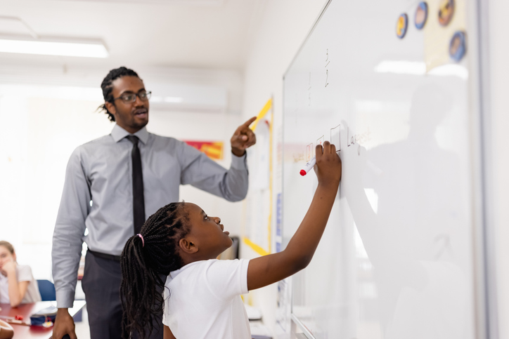 Primary School Teacher and students In Classroom