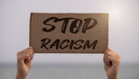 woman holding up a sign against racism